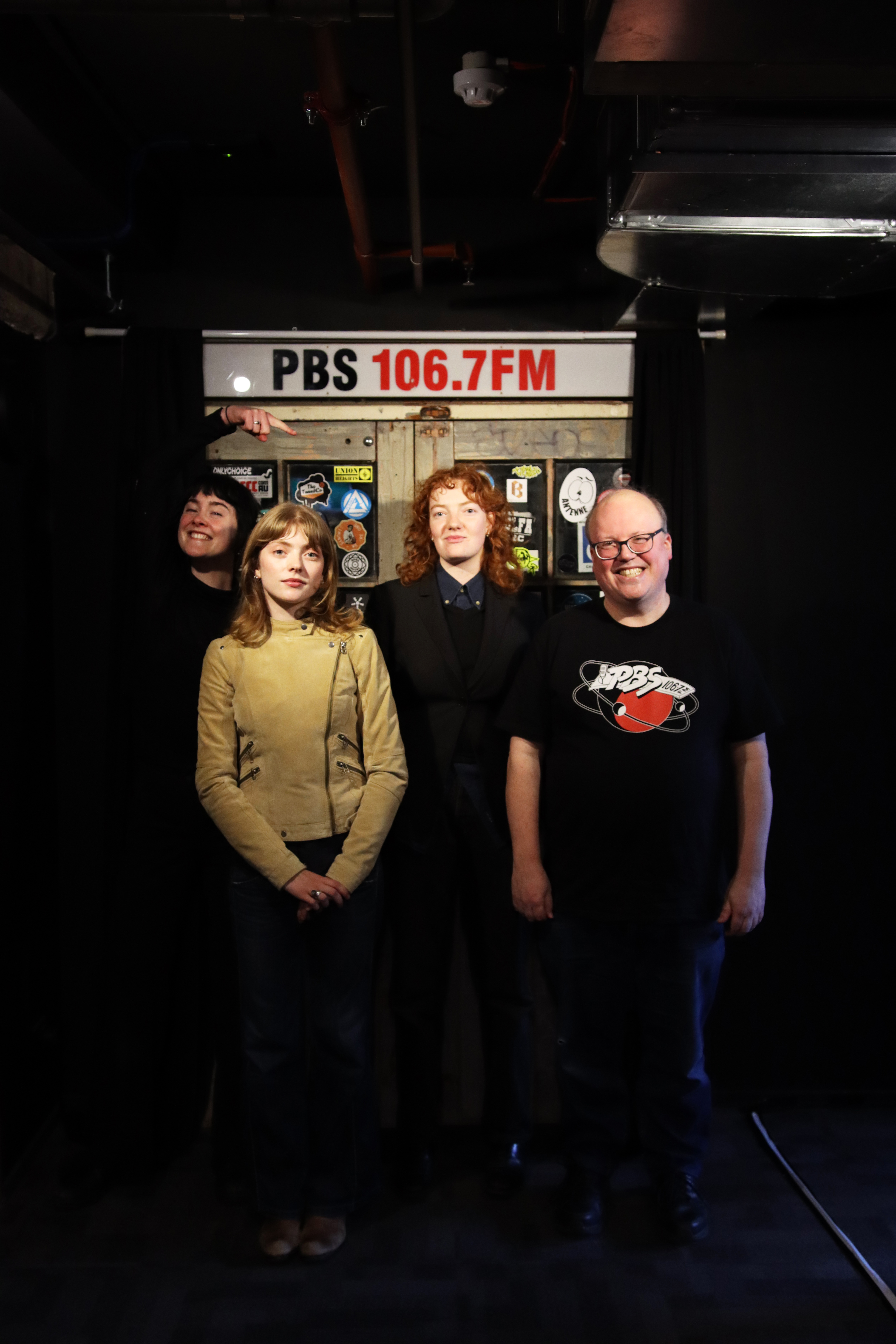 Crispi stands straight with Folk Bitch Trio in front of the PBS doors