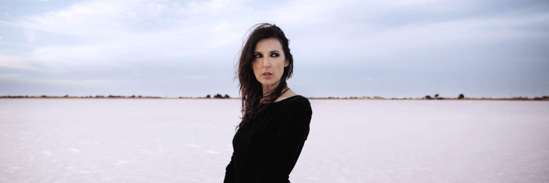 Adalita standing on a beach wearing black.