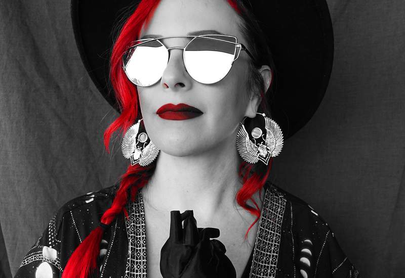 Kristen Solury with red hear and lipstick, wearing reflective sunglasses holding a black heart.
